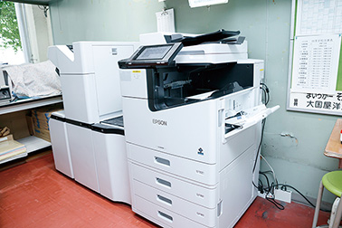 初等学校の職員室内印刷室には、中綴じフィニッシャーを装備したLX-10050MFを設置