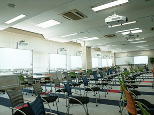 従来パーテーションで仕切られていた2つの教室を1つにまとめ、大きな教室に11台のホワイトボード機能付きプロジェクターを導入。1台につき4名程度で議論できる環境を整えた。