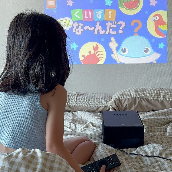 ベッドにプロジェクターを置いて映像を楽しむ子どもの様子です