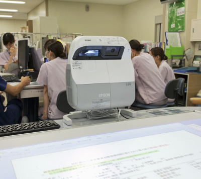広いテーブルのサイドに設置された「EB-485WT」。机を囲むICUでのカンファレンスにマッチした設置方法。